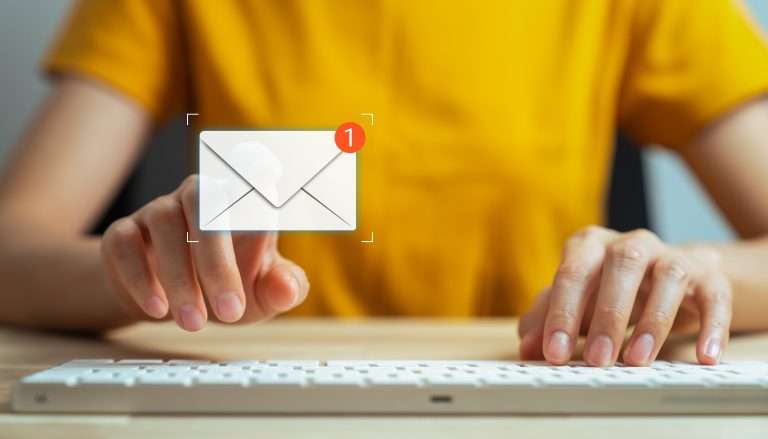 email graphic hovering above a keyboard with person typing