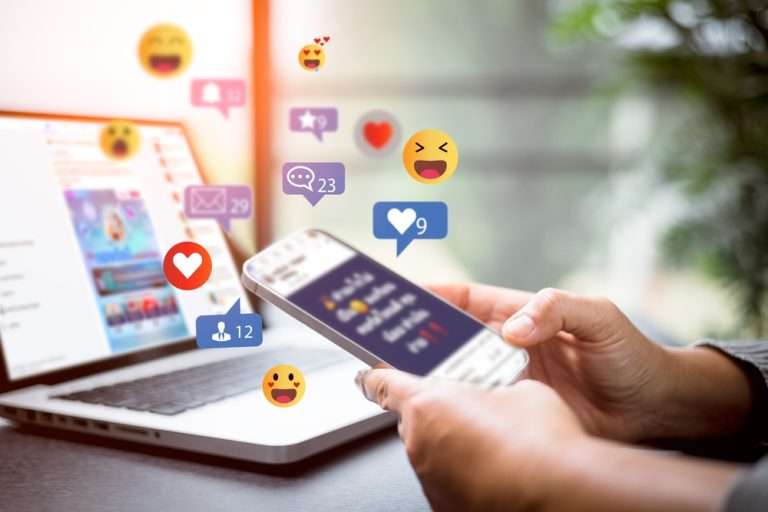 Iphone receiving likes and comments with a laptop behind it